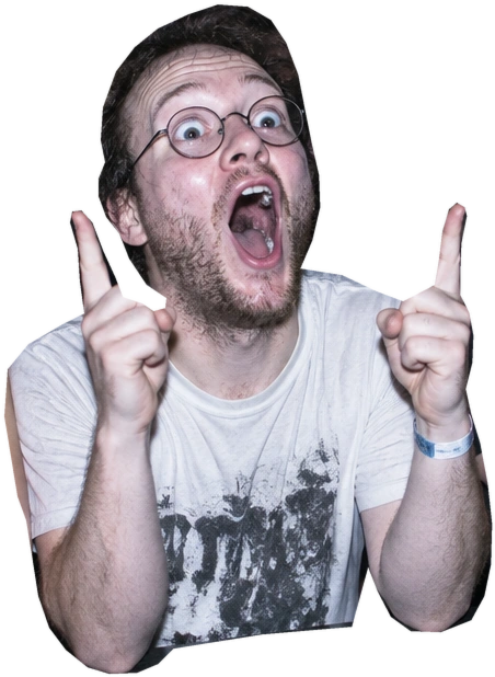 Front Row Soyboy: wild eyes behind round glasses, patchy beard, mouth open in a delighted scream, both index fingers pointing at the stage.